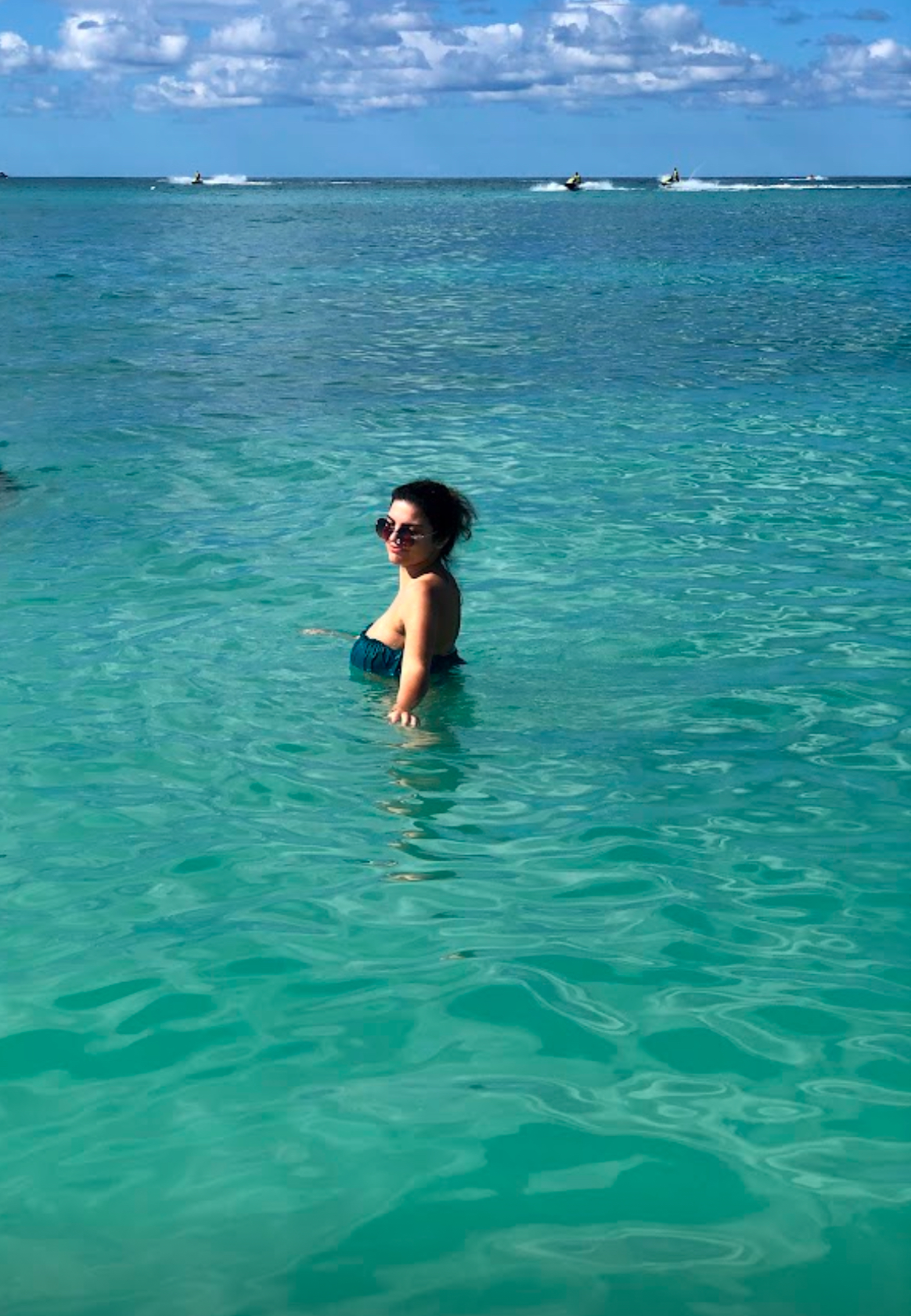 Swimming in turquoise Caribbean waters with jet skis in the distance