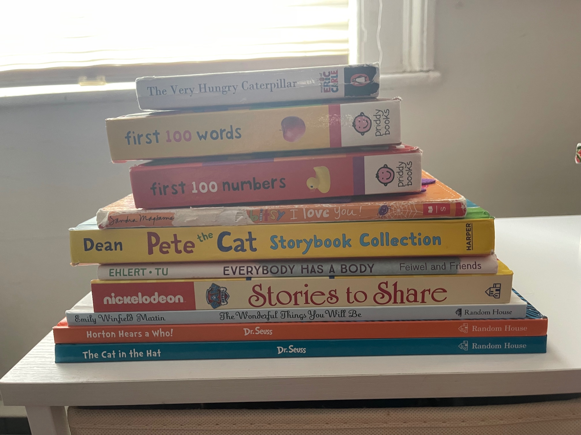 A neatly stacked pyramid of children's picture books including The Very Hungry Caterpillar, Pete the Cat, and Dr. Seuss titles